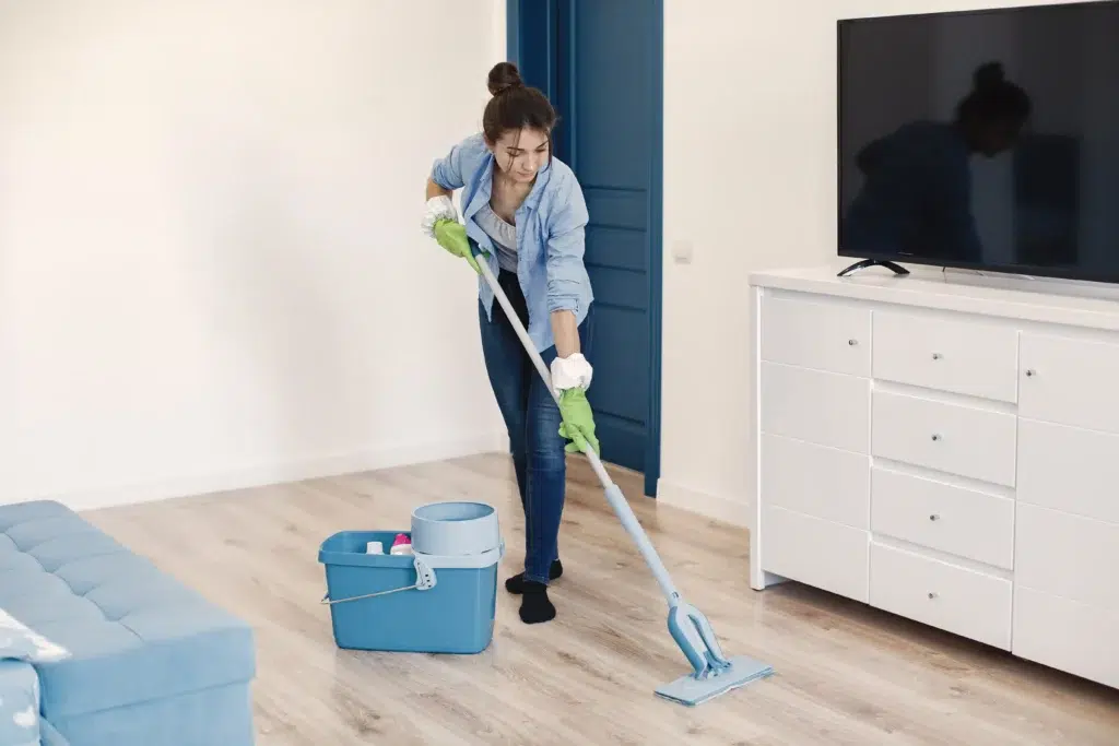 Professional cleaner mopping a modern living room during fall deep cleaning in Staten Island