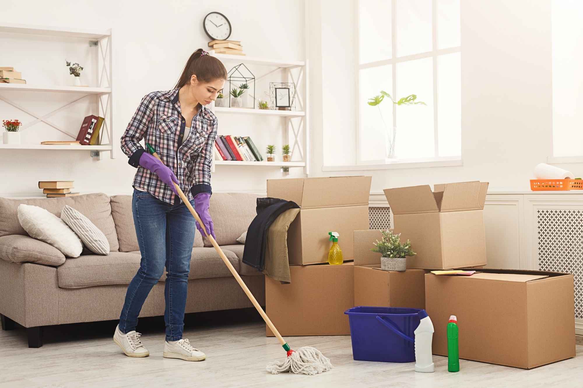 Woman mopping floor surrounded by moving boxes during a move-out cleaning session