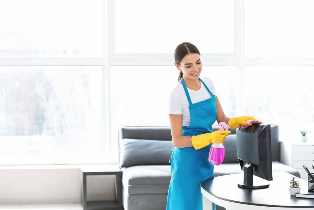 Professional office cleaning services in Staten Island – Woman cleaning a desk in a modern workspace